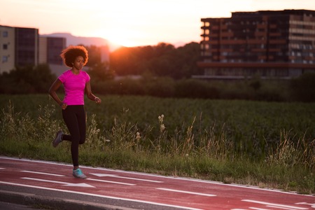 young beautiful African American woman enjoys running outside beautiful summer evening in the cityの写真素材