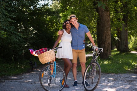 a young man and a beautiful African American girl enjoying a bike ride in nature on a sunny summer dayの写真素材