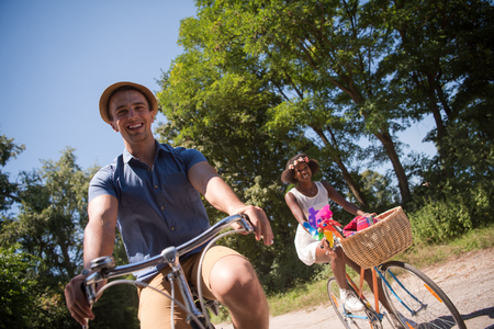 a young man and a beautiful African American girl enjoying a bike ride in nature on a sunny summer dayの写真素材