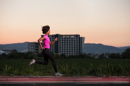 young beautiful African American woman enjoys running outside beautiful summer evening in the cityの写真素材