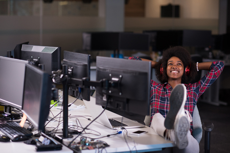 portrait of a young successful African American beautiful woman who enjoys spending a quality and joyful time while working in a large modern officeの写真素材