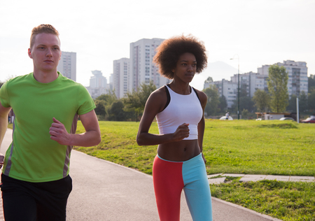multiethnic group of young people on the jogging beautiful morning as the sun rises in the streets...