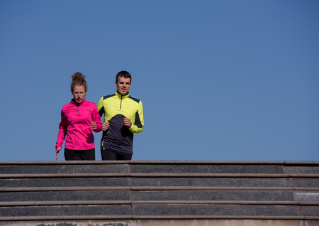 healthy young  couple jogging on steps  at early morning