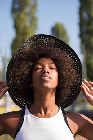 Close up portrait of a beautiful young african american woman smiling and looking up on a beautiful sunny dayの写真素材