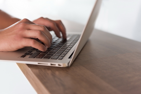 close up of male hands while typing on laptop computer in modern officeの写真素材