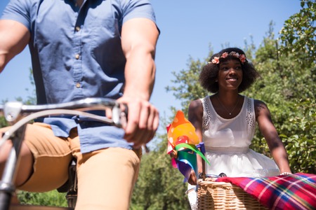 a young man and a beautiful black girl enjoying a bike ride in nature on a sunny summer dayの写真素材