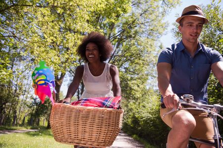 a young man and a beautiful black girl enjoying a bike ride in nature on a sunny summer dayの写真素材