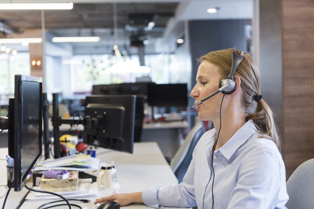 female customer support phone operator with headset  at workplace