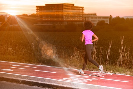 young beautiful African American woman enjoys running outside beautiful summer evening in the city