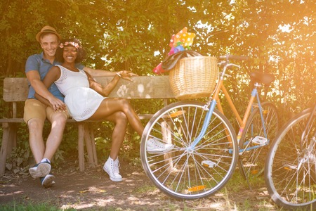 a young man and a beautiful African American girl enjoying a bike ride in nature on a sunny summer dayの写真素材