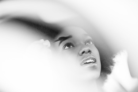 young beautiful African American woman enjoys while makeup herself in the carの写真素材