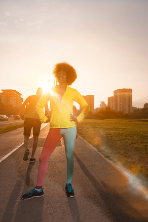 portrait of a young African American girl to run beautiful summer morning on city streetsの写真素材