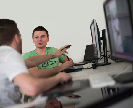 a group of young graphic designers working on a digital tablet and a computer