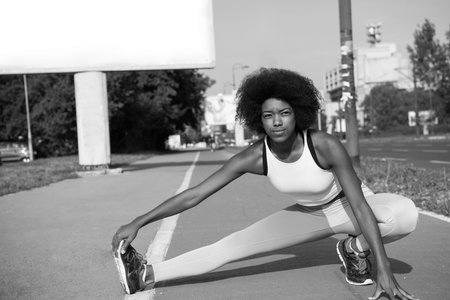 portrait of a young beautiful African American girl doing stretching beautiful summer morning on the...