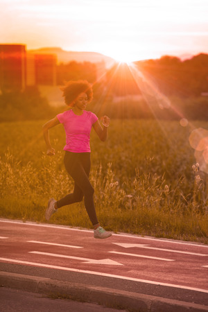 young beautiful African American woman enjoys running outside beautiful summer evening in the cityの写真素材