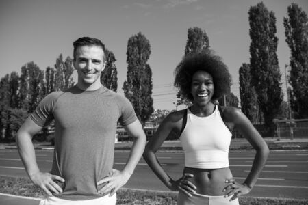 portrait of a young African American beautiful woman and a young man jogging in the cityの写真素材