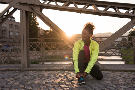 African american woman runner tightening shoe lace - Fitness, people and healthy lifestyleの写真素材