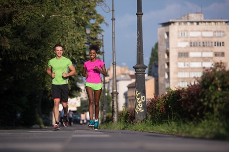 healthy young multiethnic couple jogging in the city on a sunny summer dayの写真素材