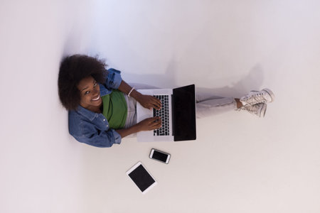 Portrait of happy young african american woman sitting on floor with laptop top viewの写真素材