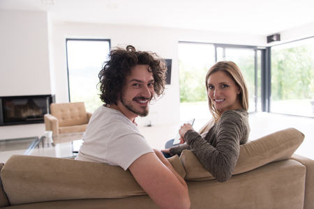 Rear view of couple watching television in living room their luxury homeの写真素材