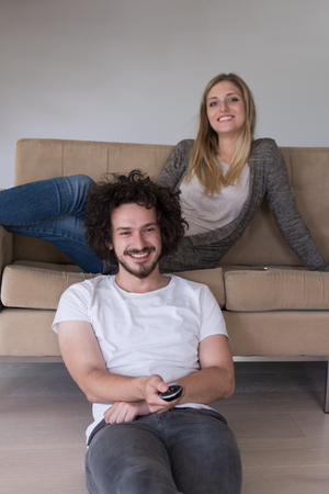 Young couple on the sofa watching television together in their luxury homeの写真素材