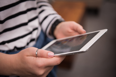 Close-up photo of female hands working with tablet computer. Woman using social network, texting and bloggingの写真素材
