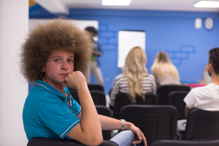 Portrait of smiling young informal businessman with colleagues in background at the office
