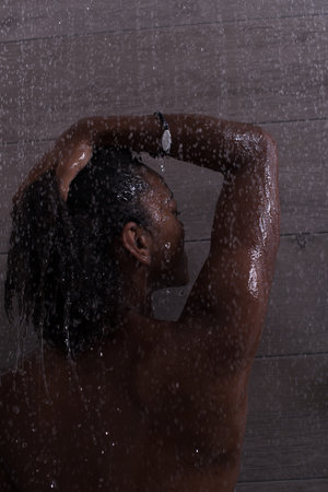 Woman in the shower,beautiful black young female showering under refreshing water, healthy lifestyle, enjoying time in luxury spa resortの写真素材