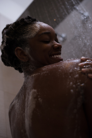 Woman in the shower,beautiful black young female showering under refreshing water, healthy lifestyle, enjoying time in luxury spa resortの写真素材