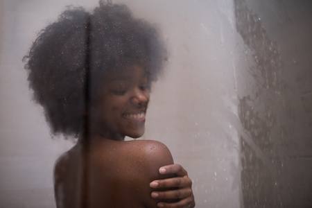 Woman in the shower,beautiful black young female showering under refreshing water, healthy lifestyle, enjoying time in luxury spa resortの写真素材