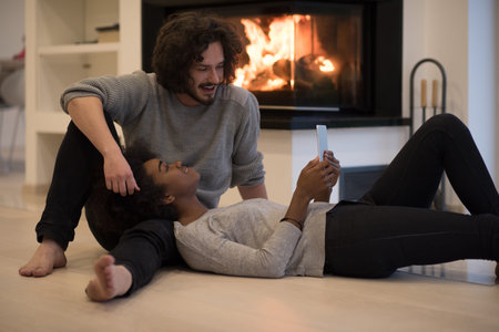 beautiful young multiethnic couple used tablet computer on the floor of their luxury home in front...