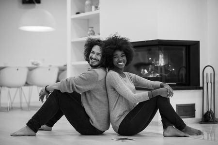 beautiful young multiethnic couple used tablet computer on the floor of their luxury home in front of fireplace autumn dayの写真素材
