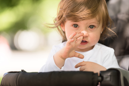 little and very beautiful baby girl sitting in the pram and waiting for momの写真素材
