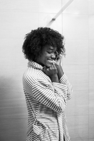 Portrait of young beautiful black woman wearing  bathrobe standing in the bathroomの写真素材
