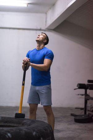Sledgehammer Tire Hits young muscular man workout at gym with hammer and tractor tireの写真素材