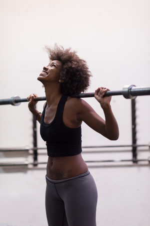 Young Cute african american sport woman in fitness room lifting empty barの写真素材