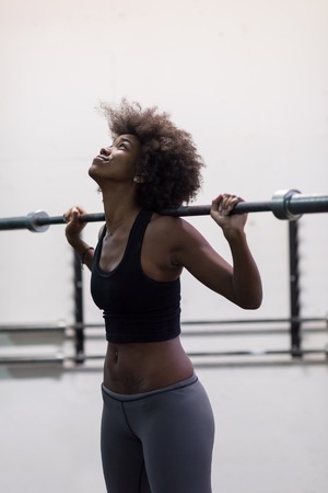 Young Cute african american sport woman in fitness room lifting empty barの写真素材