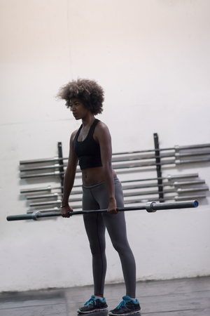 Young Cute african american sport woman in fitness room lifting empty barの写真素材