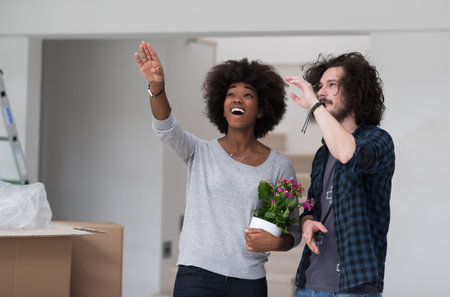 Happy young multiethnic couple unpacking or packing boxes and moving into a new homeの写真素材