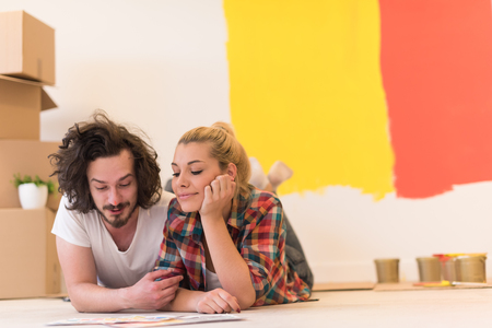 Happy young couple relaxing after painting a room in their new house on the floorの写真素材