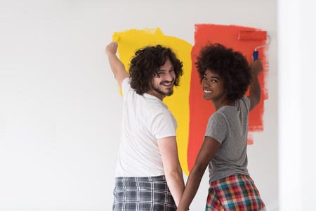 happy young multiethnic couple painting interior wall of new houseの写真素材