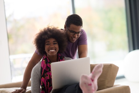 Happy young african american couple shopping online through laptop using credit card at homeの写真素材