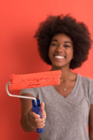 portrait of a young beautiful African American woman painting wall in her new apartmentの写真素材