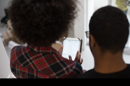 Rear view of young african american couple using tablet at homeの写真素材