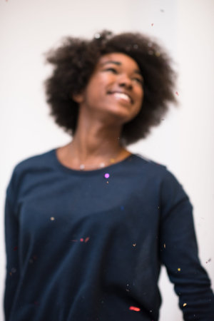 beautiful young black woman celebrating new year and chrismas party while blowing confetti...