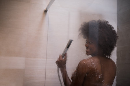 Woman in the shower,beautiful black young female showering under refreshing water, healthy lifestyle, enjoying time in luxury spa resortの写真素材