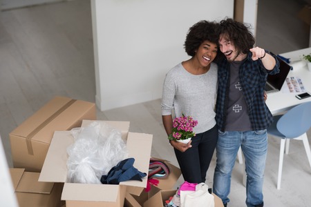 Happy young multiethnic couple unpacking or packing boxes and moving into a new homeの写真素材