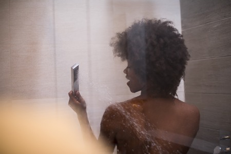 Woman in the shower,beautiful black young female showering under refreshing water, healthy lifestyle, enjoying time in luxury spa resortの写真素材
