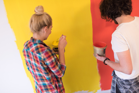 happy smiling young couple painting interior wall of new houseの写真素材