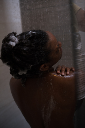 Woman in the shower,beautiful black young female showering under refreshing water, healthy lifestyle, enjoying time in luxury spa resortの写真素材